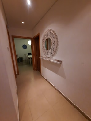Stylish hallway with a decorative mirror, shelf, and door leading to another room.