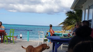 Un restaurante junto a la playa con terraza y vistas al océano.