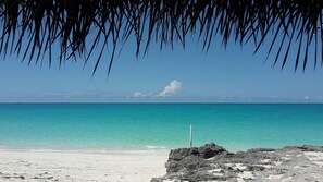 A beach with clear turquoise water, a white sandy shore, and a rocky outcrop in the foreground. - New 2 bed 2 bath Villa - near George Town and minutes from the beach! (George Town)