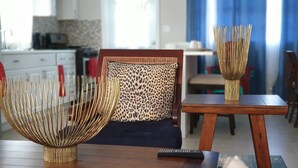 Un comedor con una mesa de madera, dos sillas con cojines estampados y un jarrón dorado decorativo.