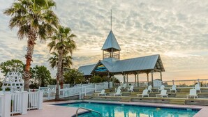 A pool area with lounge chairs and a pavilion structure. - Wayfarer cottage with elevator and Heated pool! (St Simons Island)