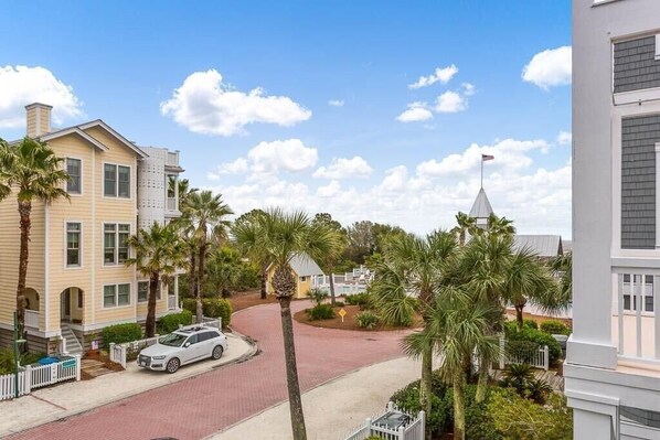 A residential street with houses, palm trees, and a church steeple.