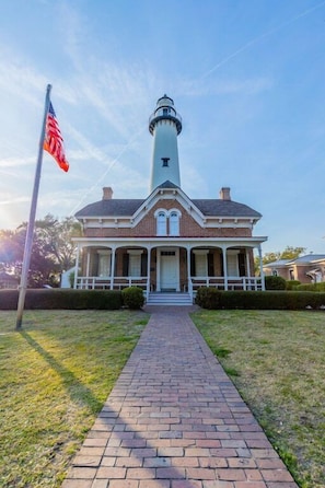 A brick building with a white porch and a lighthouse tower.