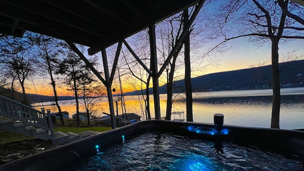 Un jacuzzi con vista a un lago y al atardecer.