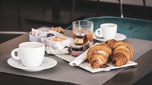 Aamiaispöytä, jossa on croissantteja, kahvia ja hilloa.