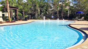 Ein Schwimmbecken mit Backsteinbordstein, umgeben von Liegestühlen und einer Pergola.