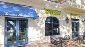 Ein Gebäude mit einer blauen Markise, auf der “Seacrest Sundries” steht, und einem Schild mit der Aufschrift “Kaffee & Wein.”