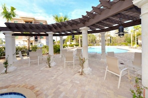 A poolside area with a pergola, lounge chairs, and a hot tub.