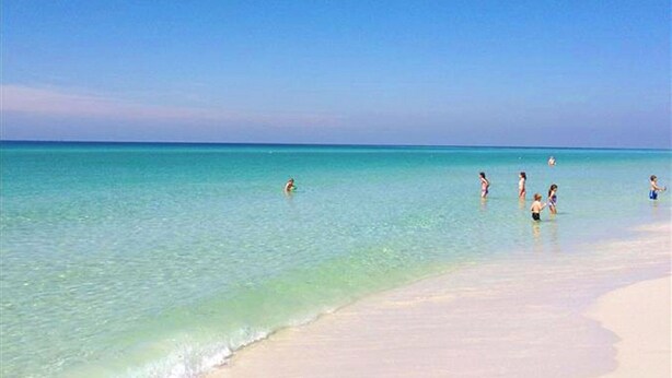 Ein Strand mit klarem türkisblauem Wasser und einem sandigen Ufer.