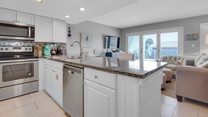 A modern kitchen with white cabinets, stainless steel appliances, and a granite countertop. - ⭐Private Beach Access-Water Views-Complex Pool-Gulfview I 216- Just Beachy⭐ (Destin)