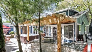 Een overdekt terras met een hottub, stenen muur en een pergola.