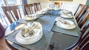 Una mesa de comedor dispuesta con platos blancos y servilletas dobladas de forma decorativa.