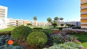 Une cour d’hôtel agrémentée de haies soigneusement taillées, d’une variété de fleurs et d’un ciel d’un bleu limpide.