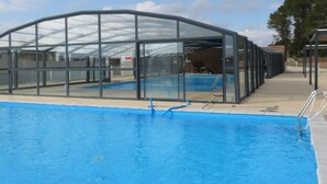 A swimming pool with a glass enclosure and a clear sky. - 5-seater cottage in Pomérols (Pomérols)