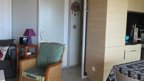 A compact living space with a wicker chair, a small table, a sofa, a kitchenette with a refrigerator, and a wall-mounted air conditioner. - 5-seater cottage in Pomérols (Pomérols)