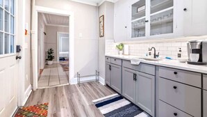 Una cocina moderna con gabinetes grises, encimera blanca y pileta de acero inoxidable.