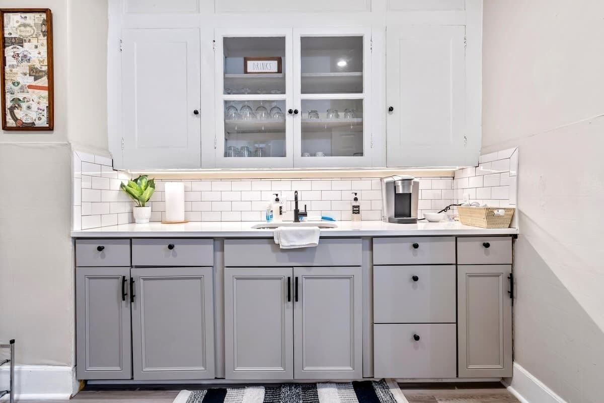 Una cocina con armarios blancos, salpicadero de azulejos y una ventana sobre el fregadero.