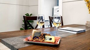Una mesa de comedor con un plato de queso y nueces, dos copas de vino blanco y un menú.