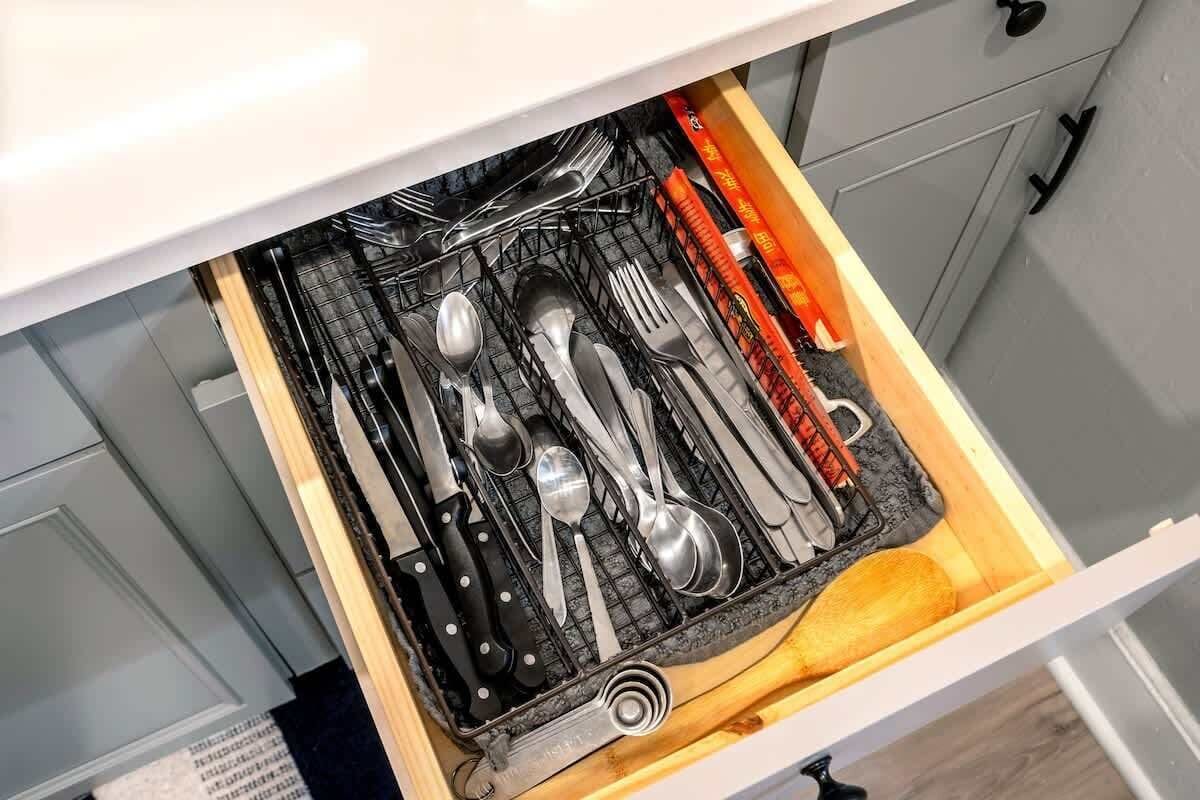 Un cajón de cocina con utensilios y un libro de cocina.
