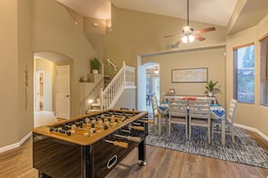 A spacious living area with a foosball table, a dining table with chairs, a staircase, and a ceiling fan. - Boulder MT Highlands: Near Golf & Trails, POOL w/Opt Heat, Spa, Putt Green, King Beds & TVs All BRs (Mesa)