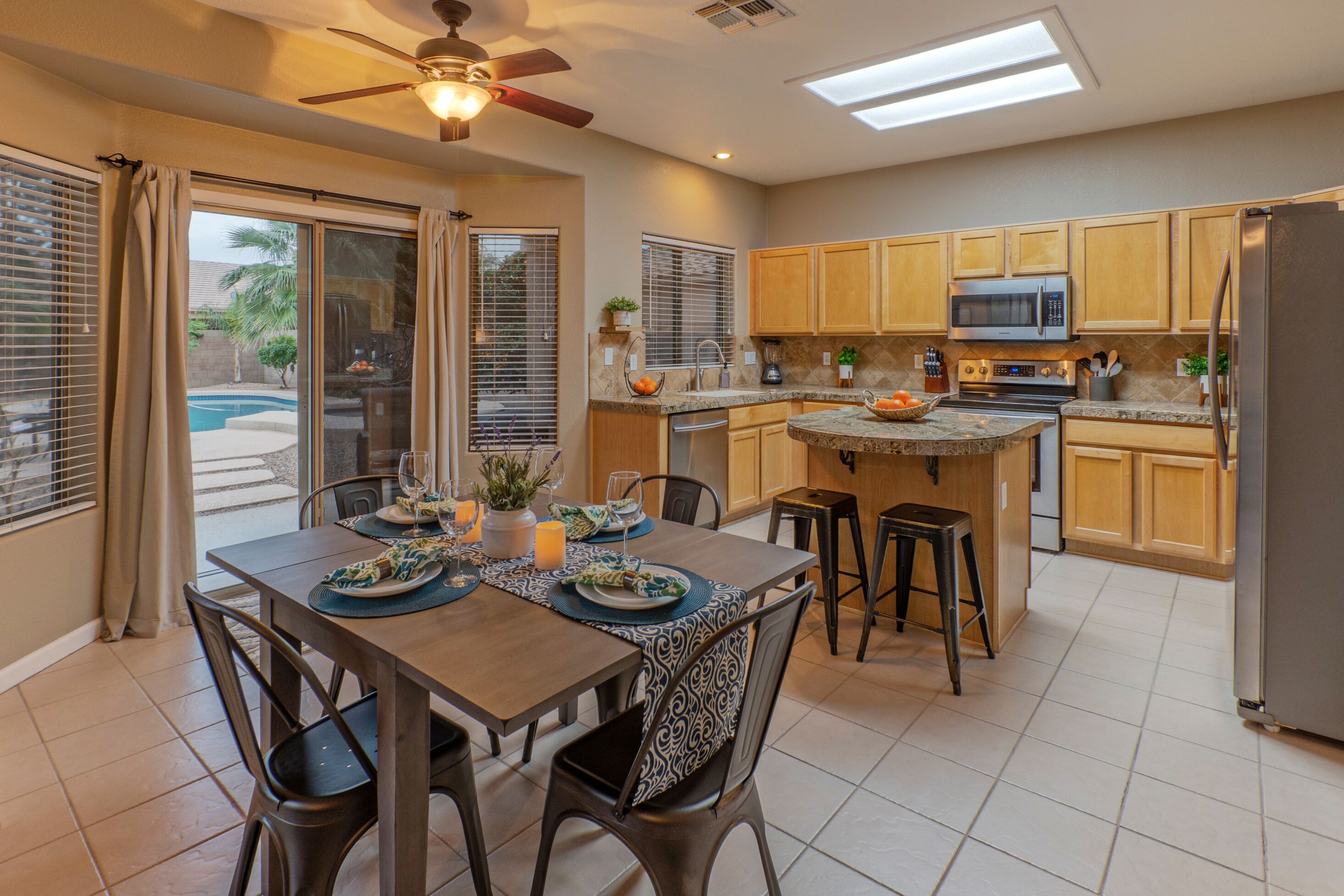 A modern kitchen with wooden cabinets, a central island, and a dining area with a table set for four.