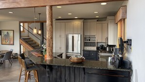 A modern kitchen with a central island, stainless steel appliances, and a wooden beam ceiling. - Comfortable large mountain home with stunning views, hot tub and pool table! (Telluride)