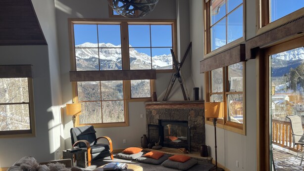 A cozy living room with a stone fireplace, large windows with mountain views, and a comfortable seating area. - Comfortable large mountain home with stunning views, hot tub and pool table! (Telluride)