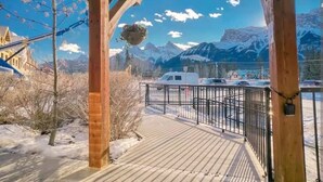 Una terraza de madera con vista a montañas nevadas y un cielo despejado.