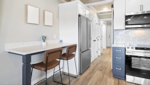 Une cuisine moderne dotée d’un plan de travail en marbre, d’appareils électroménagers en acier inoxydable et d’un revêtement de sol en bois.