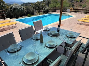 A dining area with a pool view, outdoor seating, and a table set for a meal.