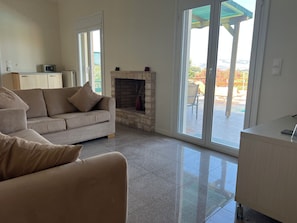 A living room with a beige sofa, a fireplace, and a sliding glass door leading to an outdoor patio.