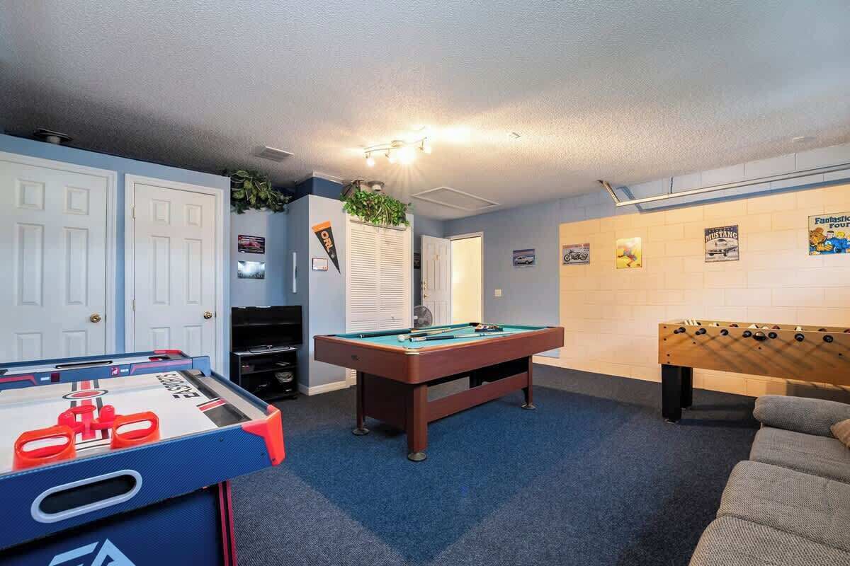 Quarto com mesa de bilhar, mesa de futebol e carpete azul.