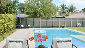 En have med swimmingpool, liggestole og en plantekasse.