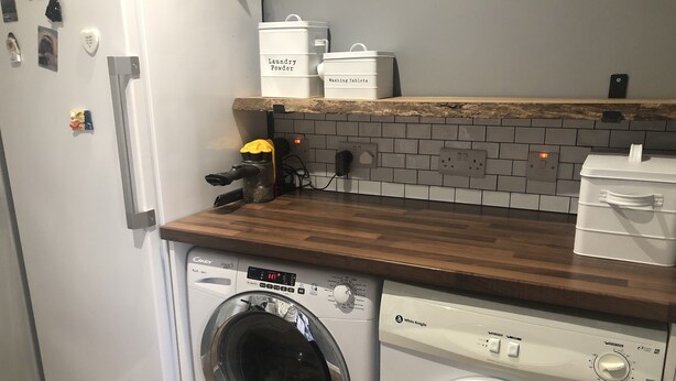 A laundry area with a washing machine and dryer, a wooden countertop, and storage containers labeled 'Laundry Powder' and 'Washing Tablets'. - St. Andrews House available for the Open (St Andrews)