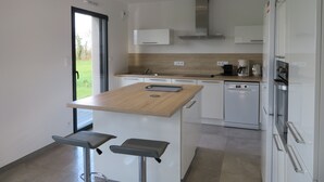 Eine moderne Küche mit einer zentralen Kochinsel, weißen Schränken und einem Geschirrspüler.