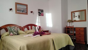 A bedroom with a bed, a dresser, a mirror, and wall-mounted artwork. - Apartments Finca House Garden (Tijarafe. La Palma)
