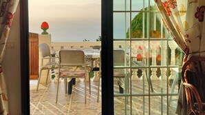 A room with a view of a terrace, a wooden door, a table with chairs, and a vase with flowers. - Apartments Finca House Garden (Tijarafe. La Palma)