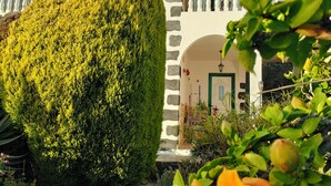 A building with a white facade, stone accents, and a balcony with railings. - Apartments Finca House Garden (Tijarafe. La Palma)