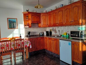 A kitchen with wooden cabinets, a microwave, a coffee maker, and a dining area with a table and chairs.