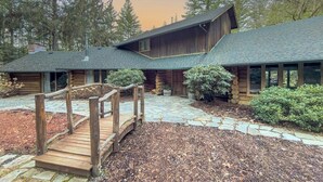 A log cabin with a stone pathway leading to a wooden deck.