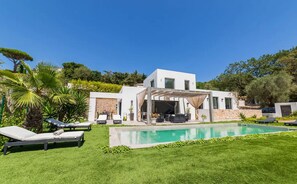 A modern house with a swimming pool, outdoor seating, and a covered patio area.