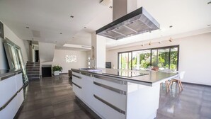 A modern kitchen with a central island, stainless steel appliances, and a large window providing a view of greenery. - ★★La Magnifique★★Piscine/Spacieux/Paisible (LE CANNET)