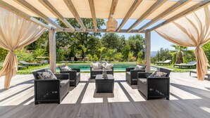A covered outdoor seating area with wicker furniture and a pool in the background. - ★★La Magnifique★★Piscine/Spacieux/Paisible (LE CANNET)