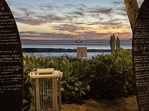 Enjoy a tranquil ocean view with a sailboat in the distance, surrounded by lush greenery and a charming outdoor dining area.