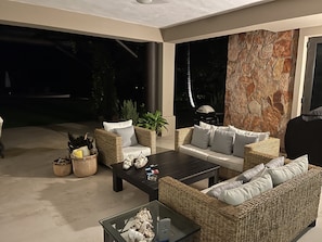Relax in a serene outdoor space with a seating area featuring wicker furniture and a glass coffee table.