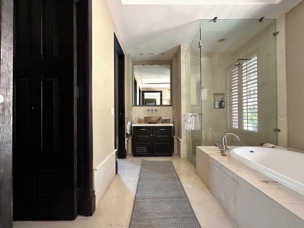 A modern bathroom with a large bathtub, a glass shower enclosure, and a vanity with a mirror.