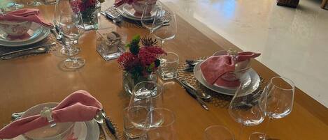 Una mesa lista para servir una comida, con varios platos, vasos y cubiertos.