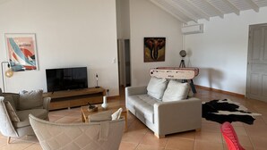 A living room with a TV, sofa, and a unique red and white object on a tripod. - Villa (Baie-Mahault)