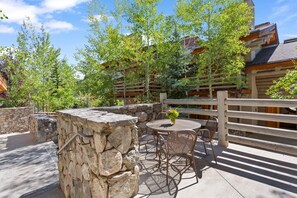 An outdoor patio with stone walls, a round table, and wicker chairs.