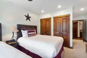 Ein Schlafzimmer mit zwei Betten, einer Stern-Dekoration an der Wand, Holztüren und einer Lampe auf einem Nachttisch.